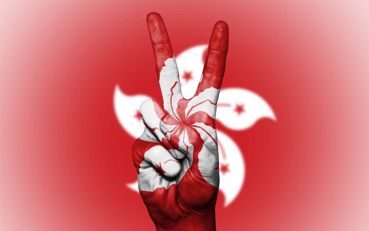 The image shows a V-for-victory salute on the background of a Hong Kong flag. Beijing is determined to smash the city’s pro-democracy movement.